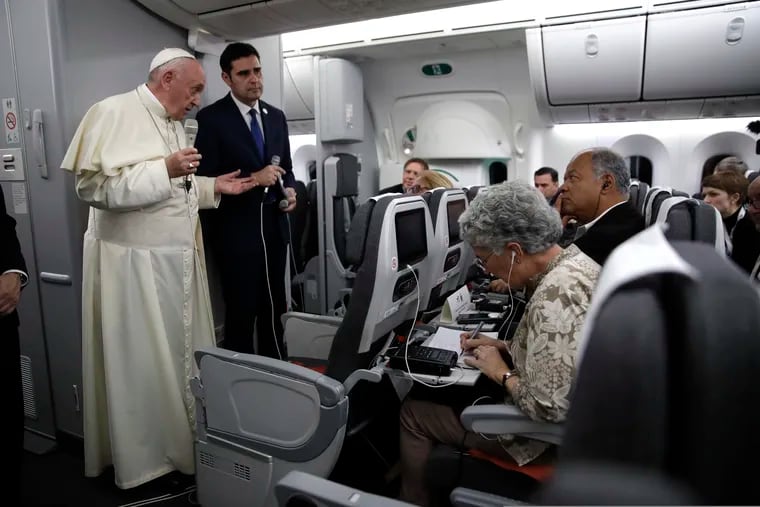 Pope Francis, flanked by Vatican spokesman Alessandro Gisotti, answers reporters' questions aboard his plane after taking off from Panama City on Sunday.