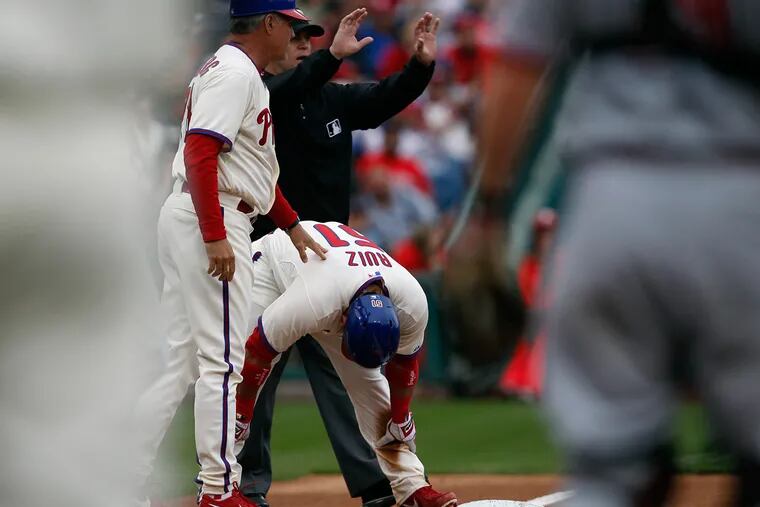 Third-base coach Ryne Sandberg checks on Carlos Ruiz after he doubled over in pain during the second inning. (David Maialetti / Staff Photographer)