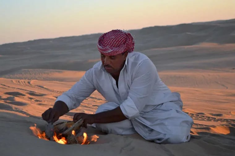 This September 2012 photo shows desert safari driver Ahmed Bakrin building a small bonfire to make mint tea before sunset during a trek through the Great Sand Sea outside the Egyptian oasis of Siwa, a Berber town of some 27,000 people roughly 450 miles (about 725 kilometers) southwest of Cairo. The palm tree-lined area is known for its quiet charm, ancient ruins, abundant natural springs, a vast salt lake and rolling sand dunes in the surrounding desert. (AP Photo/Kim Gamel)