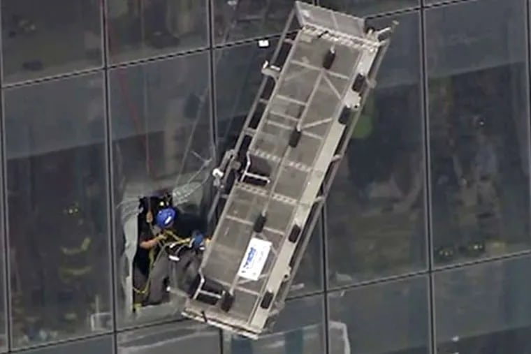 Two workers are pulled to safety by New York City firefighters from scaffolding outside the 69th floor of1 World Trade Center Wednesday. The firefighters cut through the skyscraper's thick glass.
