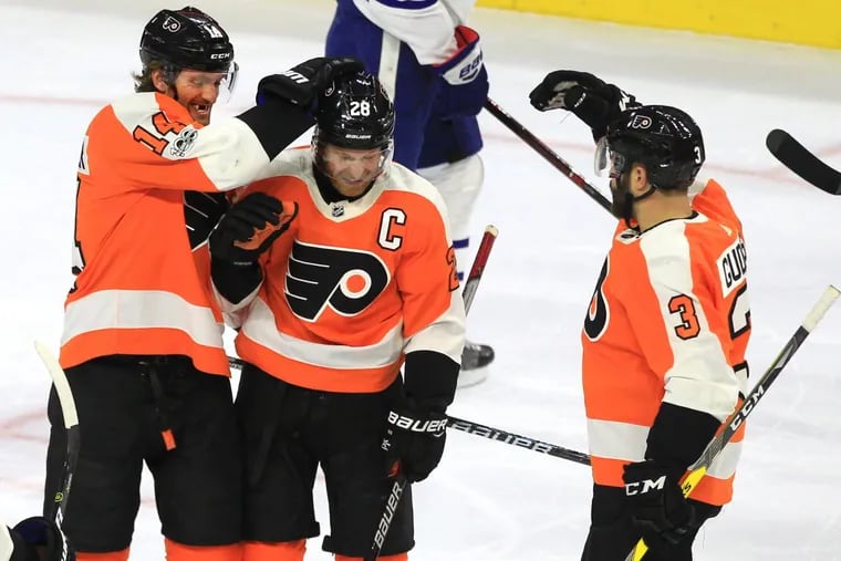Sean Couturier, left, and Radko Gudas of the Flyers celebrate with Claude Giroux after his goal against the Maple Leafs during the first period.