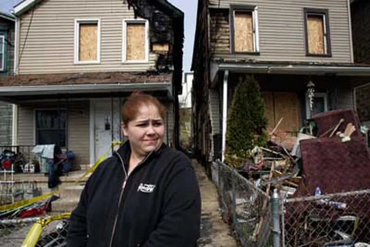 Carmen Lemus surveys the damage to her house on Valley Road in Coatesville after an early morning arson fire on March 14. A Coatesville firefighter was charged Monday for setting two fires on March 20. (Laurence Kesterson / Staff Photographer)