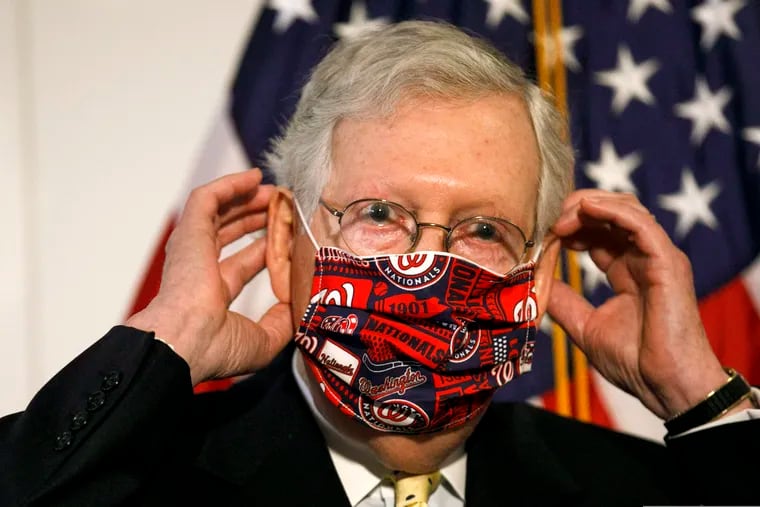 Senate Majority Leader Mitch McConnell of Ky., replacing his face mask after speaking at a news conference Tuesday.