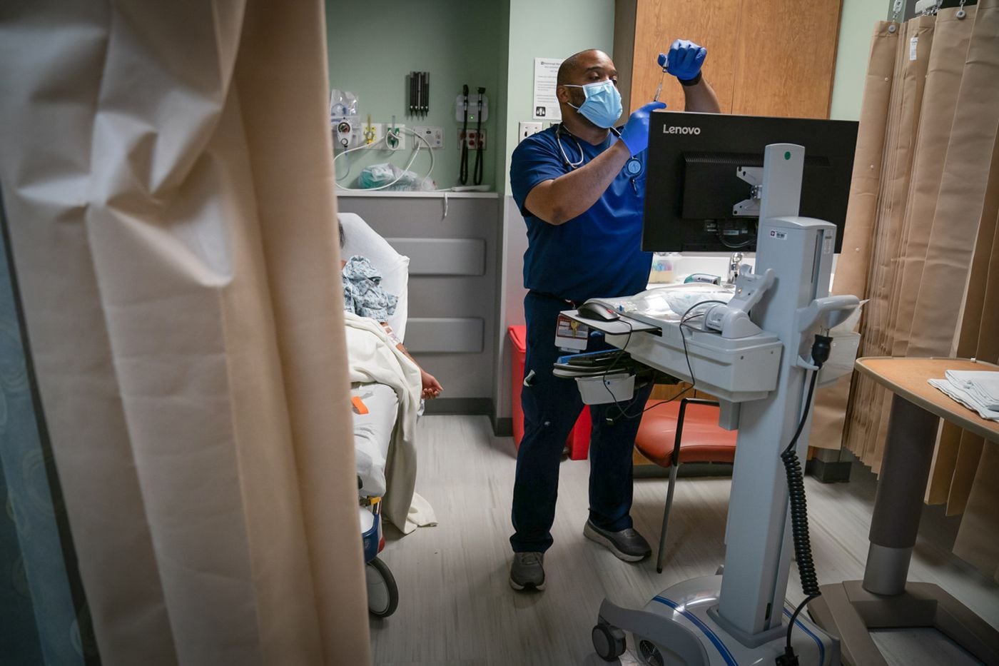ER nurse Micah Maxton treats a patient with a severe migraine at Roxborough Memorial Hospital in Philadelphia last month. Maxton, who grew up in North Philadelphia, lost an aunt, cousin and scores of friends and acquaintances to COVID-19.