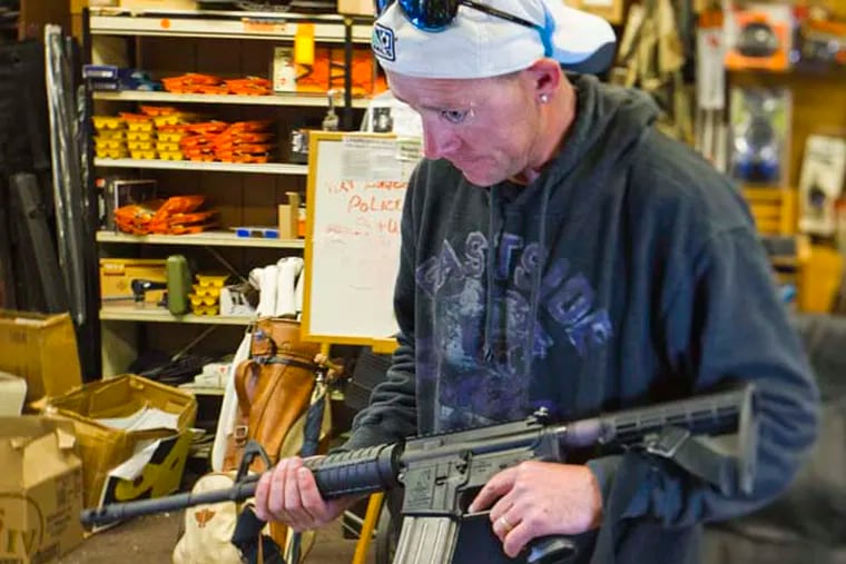 At Delia’s Gun Shop in Northeast Philadelphia, John McCarrapher of Frankford handles an AR-15 rifle. McCarrapher said he was looking to purchase his first handgun.