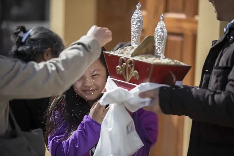 Tenzin Dhakar, 9, holds a container of rice and barley flour as part of Sunday's dedication ceremony at the Tibetan Buddhist Center of Philadelphia.