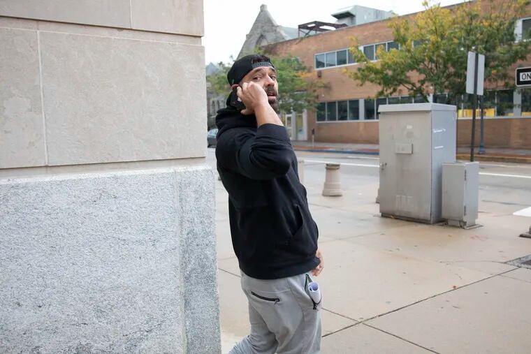 Mark D'Amico holds his phone to his ear as he waits for his ride from the federal courthouse in Camden after his initial appearance on federal charges before a magistrate judge.