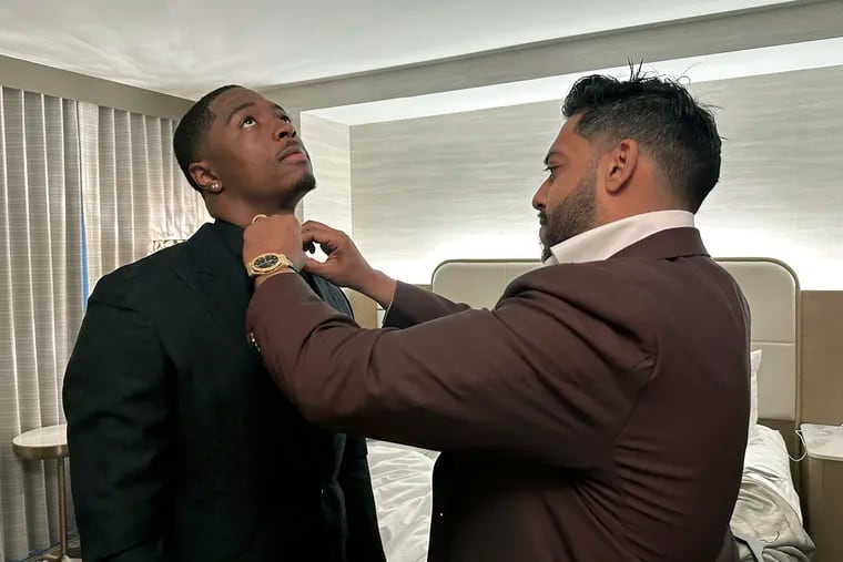 Ravi Punn, right, of Baynes + Baker, adjusts the collar on Eagles first-round pick Quinyon Mitchell during a final suit fitting for the draft on Thursday.