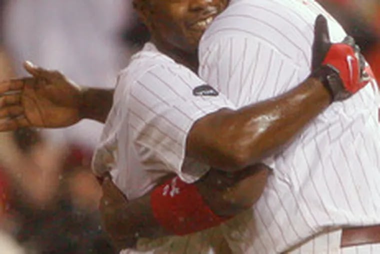 Jimmy Rollins (left) gets a hug from Ryan Howard after knocking in the winning run in the 10th.