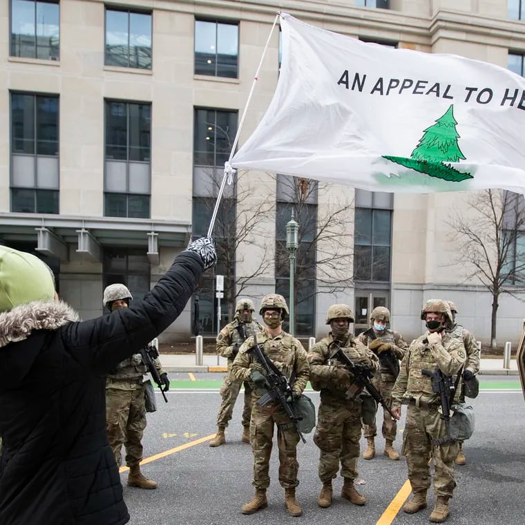 A group of women stop to pray with National Guardsmen by the State Capitol  in Harrisburg in January 2021, displaying the “Appeal to Heaven” flag.