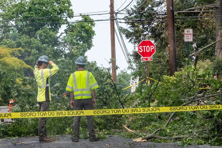 Cleaning crews work on down electrical lines and fallen trees on Wharton Road in Glenside on Thursday, one of the towns clocked by severe storms the day before.