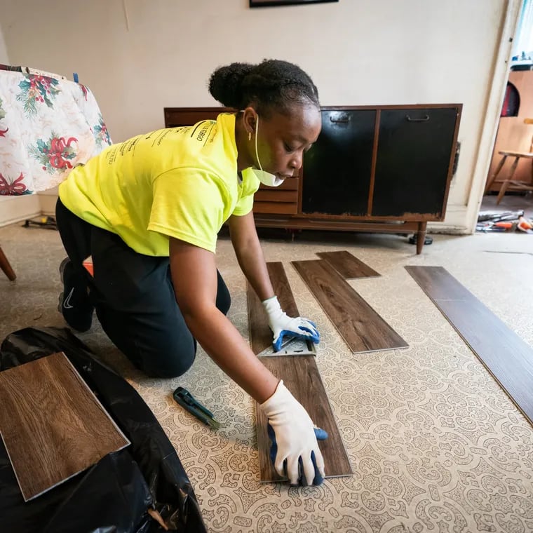 Volunteer Oyinda Alliyu installs flooring in the home of Linda Smith and Jane Stevens during an event where volunteers from the nonprofit Rebuilding Together Philadelphia work on houses in West Philadelphia.
