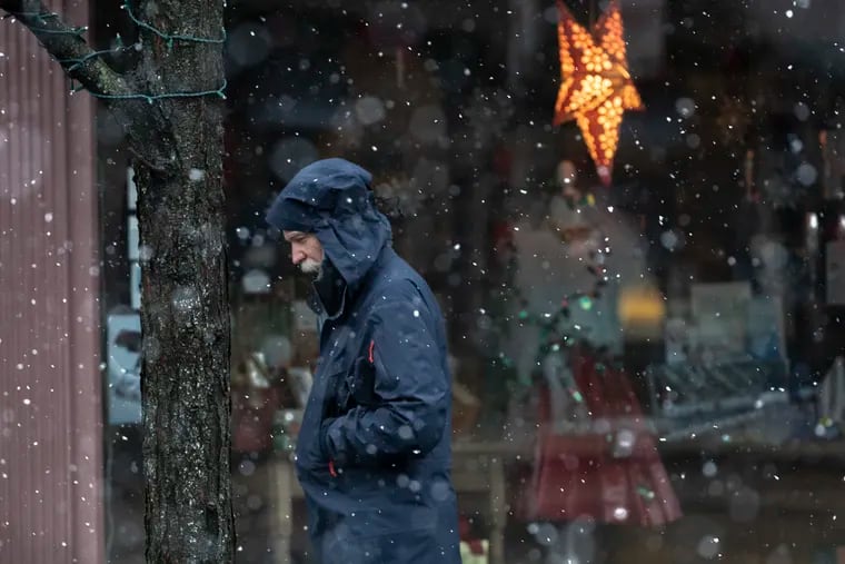 A pedestrian walks down Germantown Avenue in a light snow early Monday morning.