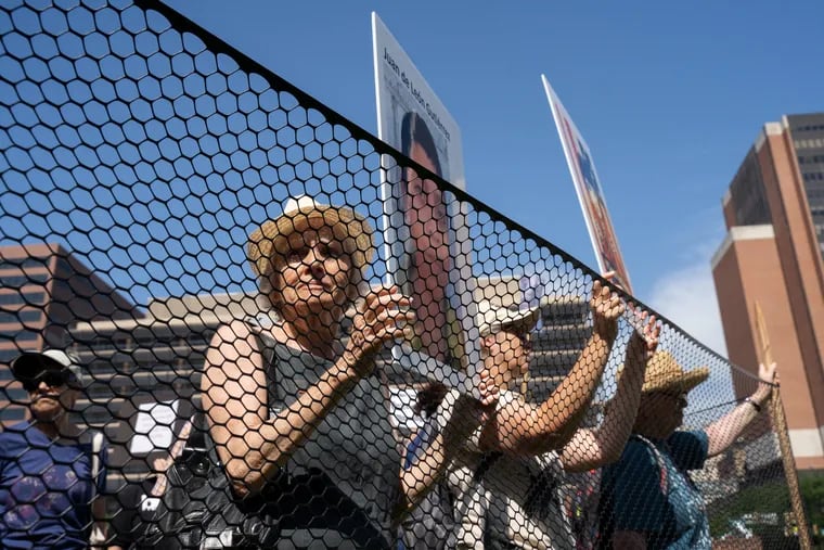 Shelly Yanoff from "ElderWitness" joins others who penned themselves inside a portable, fenced "detention center" at Independence Mall on Wednesday. They sought to dramatize the deaths of migrant children who have died in U.S. custody.