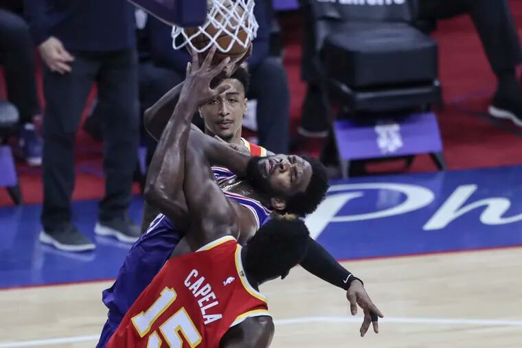 The Sixers' Joel Embiid is fouled by Atlanta's Clint Capela with John Collins behind during the second quarter of Game 5 at the Wells Fargo Center.