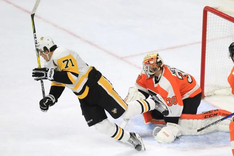 Evgeni Malkin, left, of the Penguins goes flying to the ice in front of goalie Michal Neuvirth, right, of the Flyers as Mlkin assisted on Jamie Oleksiakâ€™s goal during the 3rd period at the Wells Fargo Center on Jan. 2, 2018.