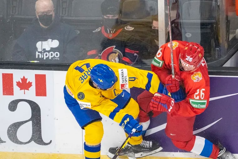Sweden's Emil Andrae (left), a 2020 second-round pick by the Flyers, hitting Russia's Kirill Tankov during world junior hockey championship action in December 2021.