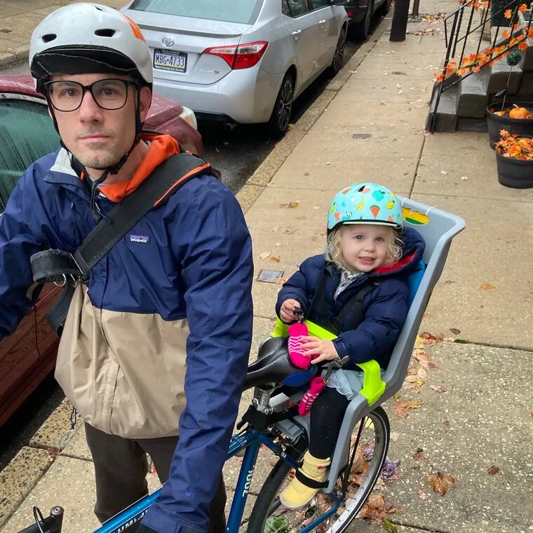 Christopher Dascher with his daughter. Parking permits that allow houses of worship to use designated bicycle lanes as private event parking every weekend are making stretches of Center City dangerous for bike riders, he writes.