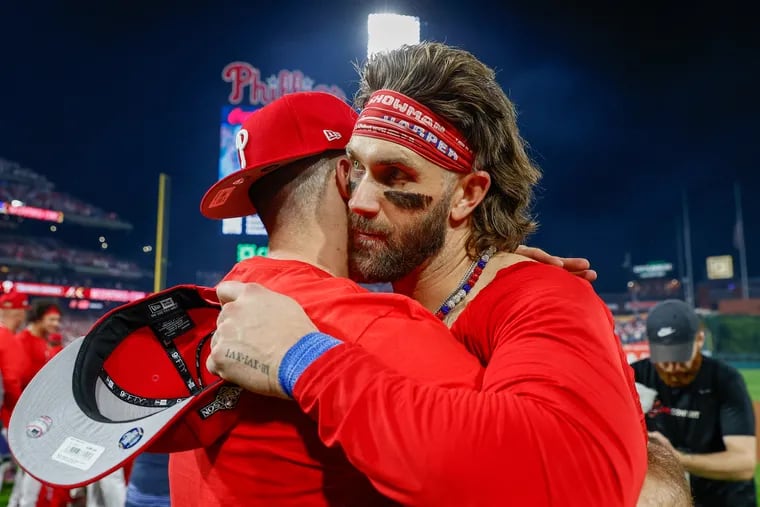 Philadelphia Phillies catcher J.T. Realmuto (left) and Bryce Harper celebrate their victory over the Marlins following Game 2 of an NL wild-card baseball series at Citizens Bank Park on Oct. 4, 2023.