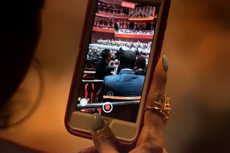 A patron records video in Verizon Hall in 2022 at the Kimmel Center.