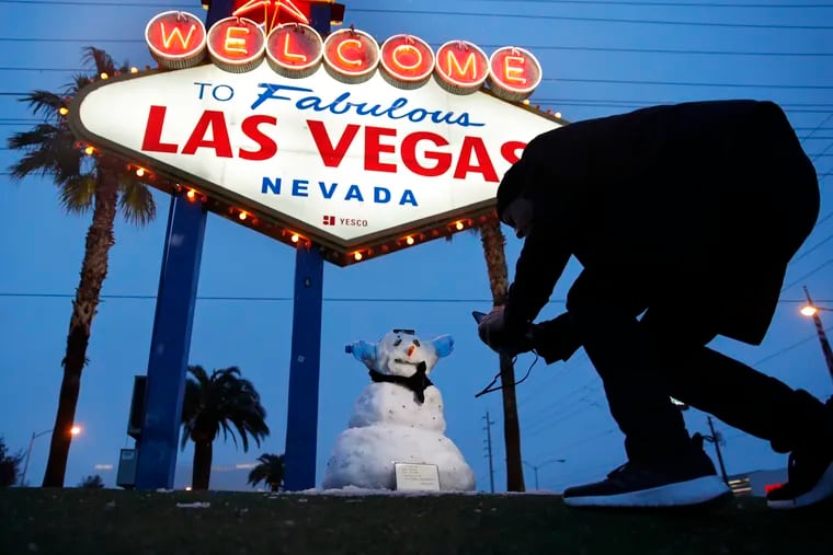 A man, who declined to give his name, takes a picture of a small snowman at the "Welcome to Fabulous Las Vegas" sign along the Las Vegas Strip, Thursday, Feb. 21, 2019, in Las Vegas. Las Vegas is getting a rare taste of real winter weather, with significant snowfall across the metro area in the first event of its kind since record keeping started back in 1937.