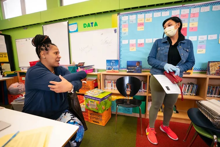 Andrea Evans (left), a first-grade teacher at Mitchell Elementary in Philadelphia, gives a no-contact hug while talking with parent Danielle Johnson, in an April Inquirer file photo. The Philadelphia School District is among those that were shortchanged by Pennsylvania's distribution of federal funding, according to a new report.