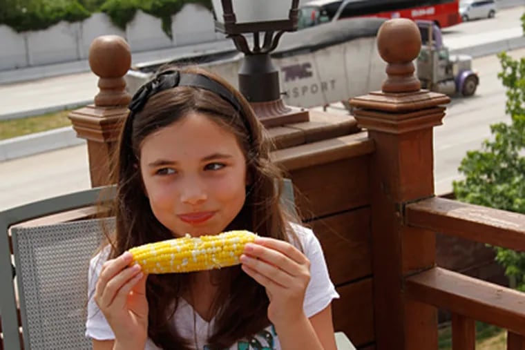 Adriana Bartolomeo, 9, eats grilled corn on the rooftop deck of Village Belle restaurant in Queen Village. (Michael S. Wirtz / Staff Photographer)