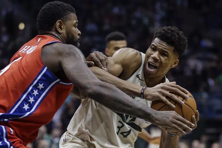 Giannis Antetokounmpo of the Bucks  is tied up by the 76ers’ Amir Johnson during the second half.