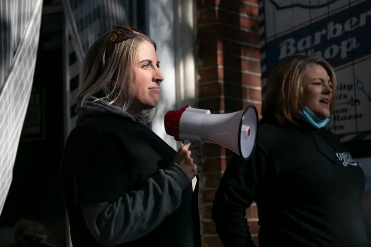 Nichole Missino (left), owner of Giovanni's Barbershop, and Felicia Stella address the crowd during a rally outside the shop in Media on Saturday.