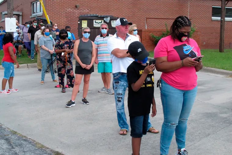 Voters wearing masks wait in line to vote early outside the Chatham County Board of Elections office in Savannah, Ga., on Wednesday, Oct. 14, 2020. Black people are going to the polls by the thousands and waiting in lines for hours to vote early in Georgia.