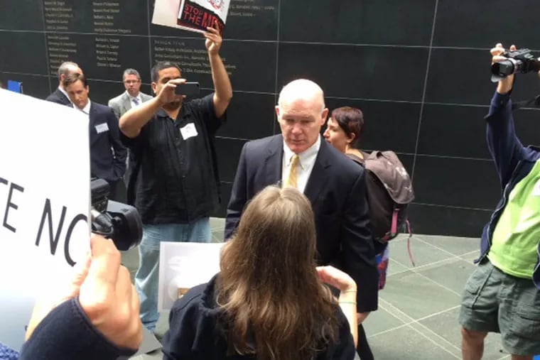 Comcast security director Joe Clancy accepts anti-merger petitions from Free Press’ Mary Alice Crim on Wednesday.