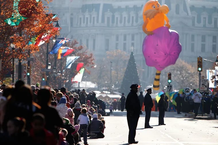Police officers stand in the parade route as a crowd gathers along the Ben Franklin Parkway during Philadelphia's Thanksgiving Day parade in 2012.