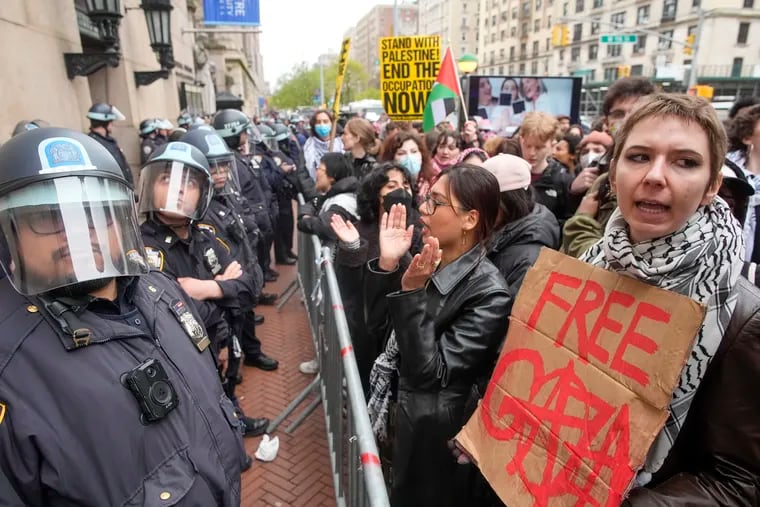 Police in Riot gear stand guard as demonstrators chant slogans outside the Columbia University campus on Thursday in New York.