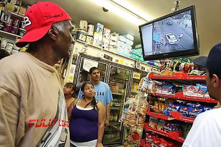 Kensington residents watch video of Jose Carrasquillo being beaten up at a store near where the incident occurred. (Steven M. Falk / Staff Photographer)
