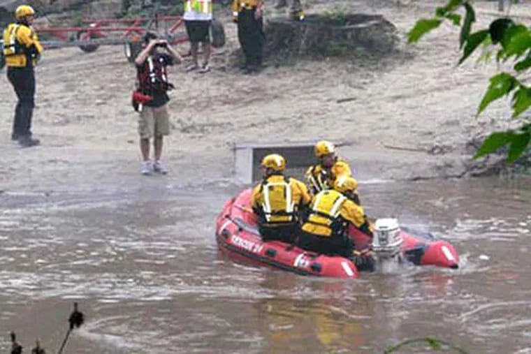 Rescue workers search Brandywine Creek for a missing kayaker in East Bradford Township. Another kayaker was pulled from the swollen creek, but died. (Kathleen Brady Shea / Staff)