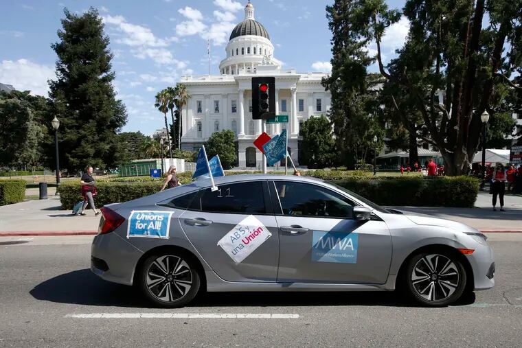 In this Aug. 28, 2019, photo, supporters of a measure to limit when companies can label workers as independent contractors drive their cars past the Capitol during a rally in Sacramento, Calif. California lawmakers are debating a bill that would make companies like Uber and Lyft label their workers as employees, entitling them to minimum wage and benefits. (AP Photo/Rich Pedroncelli, File)