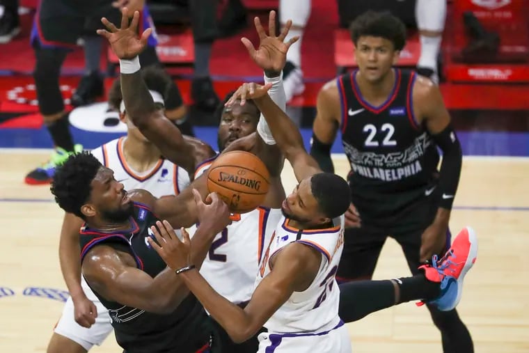 Sixers’ Joel Embiid is surrounded by Phoenix Sun defenders while going up for a shot in the first quarter of a game at the Wells Fargo Center in Philadelphia on Wednesday, April 21, 2021.
