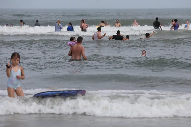 People wade into the ocean off the beach in Wildwood, N.J., on Friday, July 3, 2020. Hot weather and the Fourth of July weekend brought crowds to the Jersey Shore despite the coronavirus pandemic.