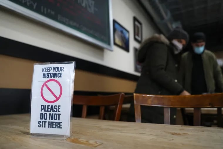 A sign marks off a table for social distancing at Green Eggs Cafe on Dickinson Street in South Philadelphia on Saturday, Jan. 16, 2021. The city said it will review changes by the state before following suit.