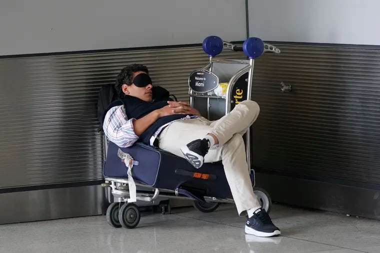 A traveler takes a nap as he waits for a ride outside Miami International Airport, in 2022.