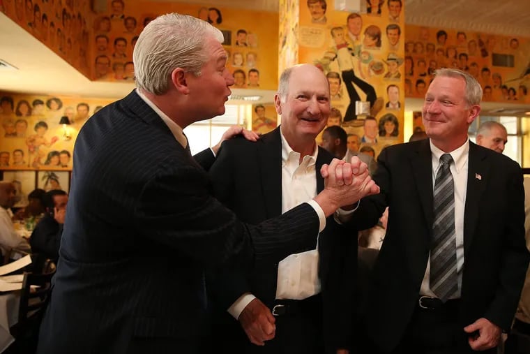 John Dougherty, left, then the head of Local 98 of the International Brotherhood of Electrical Workers, congratulates his brother, Kevin Dougherty, right, after his 2015 Democratic primary victory as a candidate for the Pennsylvania Supreme Court, as their father, John Dougherty Sr., center, smiles at The Palm Restaurant in Center City in May 2015.