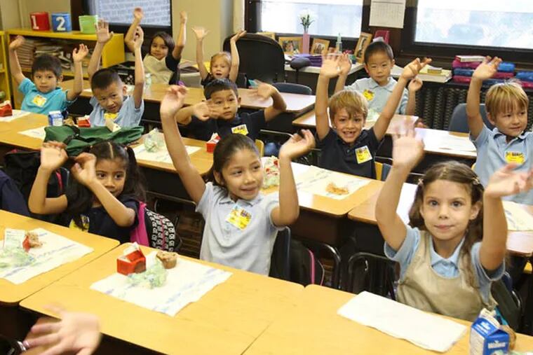 First-grade students raise their hands to show their "jagular" paws (school's mascot) at Andrew Jackson School in Philly in September 2013. A stepped-up effort by the city to collect the little-known School Income Tax, appears to be working. Just over 37M was collected from this tax, which benefits schools, in the last fiscal year. ( CHARLES FOX / Staff Photographer )