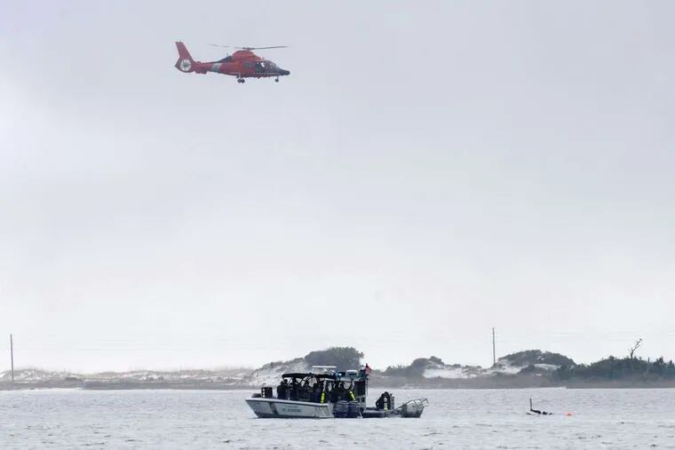 A Coast Guard helicopter and a boat with divers search the Santa Rosa Sound near Navarre, Fla., for the helicopter, which went down late Tuesday amid bad weather.