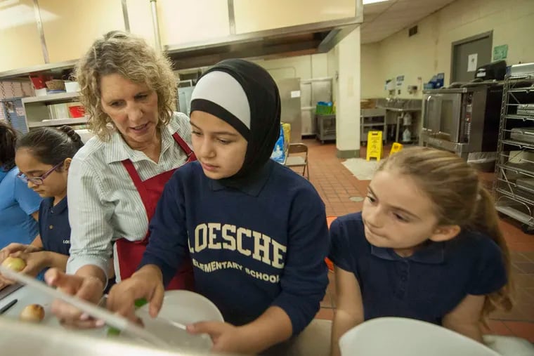 PHOTOS: CLEM MURRAY / STAFF PHOTOGRAPHER Sue Munafo (above) shows Areeg Mustafa (center) and Angela Basha (right) the casserole recipe. Natasha Carvalho (below, from center) and Andrea Cuadra join in.