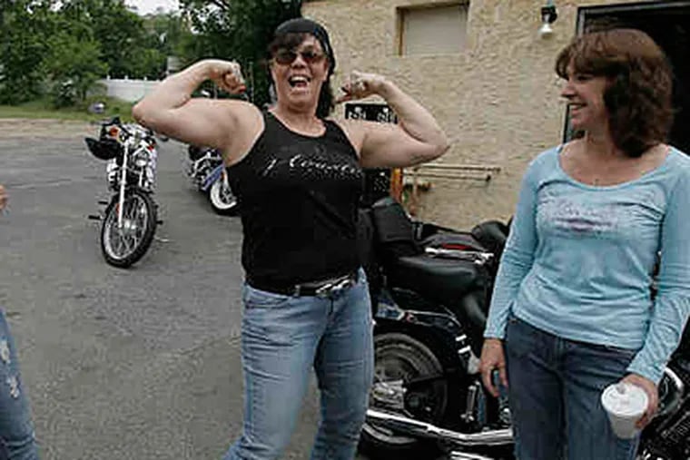 Carol Bassel, 50, flexes her muscles outside a coffee shop in Delran before taking off on a Saturday ride. With her is fellow rider Tina Ott, 47. (Akira Suwa/Staff)