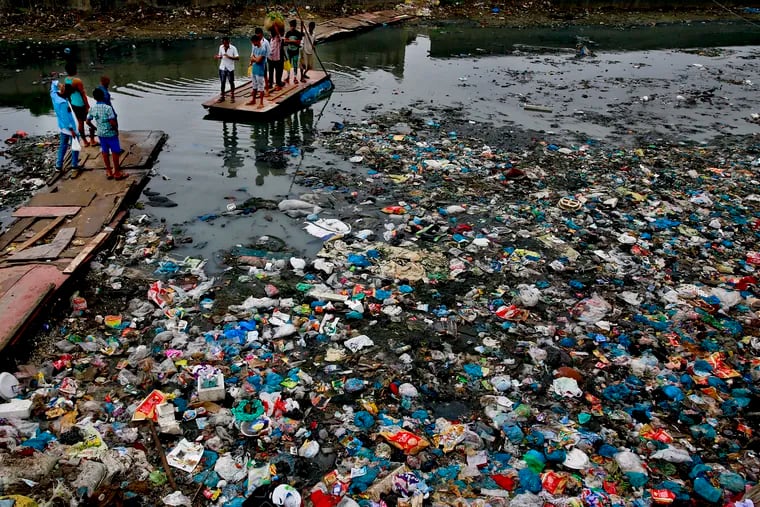 In this Sunday, Oct. 2, 2016 file photo, a man guides a raft through a polluted canal littered with plastic bags and other garbage in Mumbai, India. United Nations officials say nearly all of the world's countries have agreed on a deal to better manage plastic waste, with the United States a notable exception. A "legally binding framework" that affects thousands of types of plastic waste emerged Friday, May 10, 2019 after a two-week meeting of U.N.-backed conventions on plastic waste and toxic chemicals.