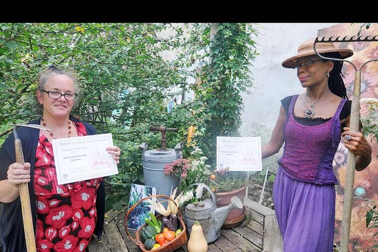 Pat Lyons (Left) and Khenti Pratt show off the many awards that the community garden has won since 1996. The garden has been recognized by the National Horticultural Society with a few prestigious awards. (PATRICK MCPEAK/STAFF PHOTOGRAHPER)