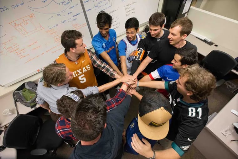 Evan Brandoff, second from top left (orange shirt), and Zubin Teherani, fourth from left (short sleeved blue T-shirt with white tank over top), lead an employee team huddle at their offices.