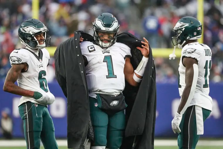 Philadelphia Eagles quarterback Jalen Hurts (1) removes his jacke to resume play next to Philadelphia Eagles wide receiver DeVonta Smith (6) and Philadelphia Eagles wide receiver A.J. Brown (11) in the first half of a game at MetLife Stadium in East Rutherford, NJ on Sunday, Dec. 11, 2022.