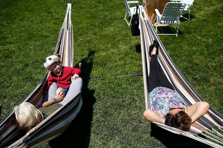 Miranda Budine and her son, Bryce, and Geraldine Lisondra (right) relaxing in hammocks after the 2017 launch of Parks on Tap in the Azalea Garden in Fairmount Park.